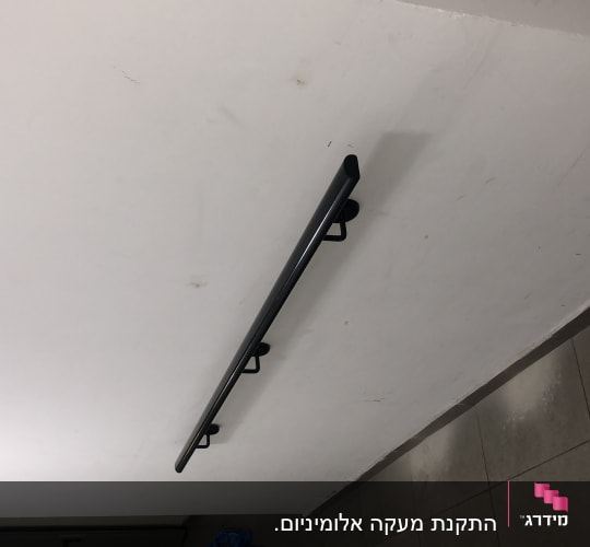 מעקה מתכת שחור מותקן על קיר לבן